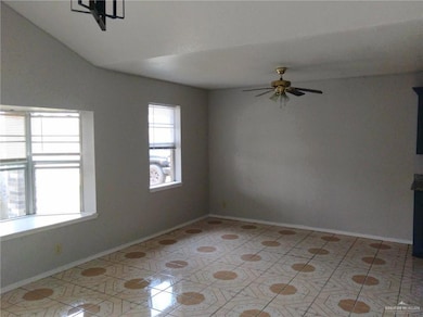 Living room with light tile patterned flooring, ceiling fan, and lofted ceiling