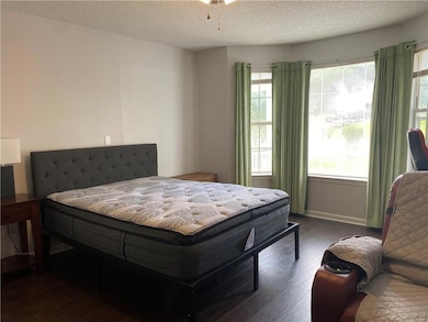 Bedroom with a textured ceiling, multiple windows,