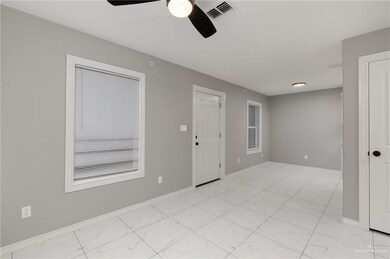 Empty room with light marble finish flooring, a ceiling fan, and baseboards