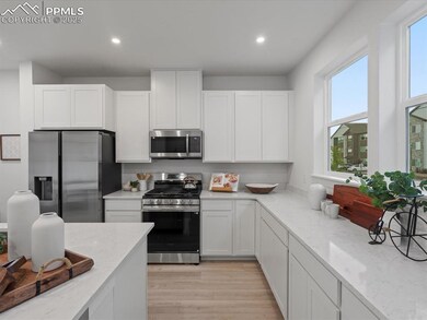 Kitchen featuring appliances with stainless steel finishes, white cabinets, light stone countertops, light wood-style flooring, and recessed lighting