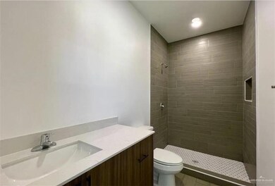 Full bath featuring a tile shower, toilet, and vanity