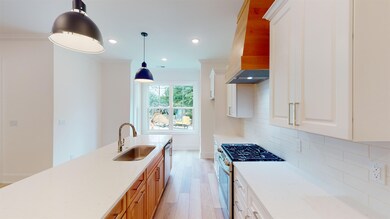 Kitchen with a sink, stainless steel appliances, ornamental molding, decorative backsplash, and light wood-style floors