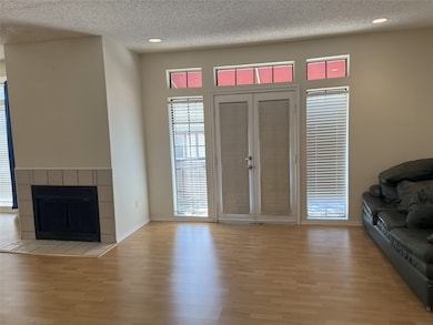 Living room with a textured ceiling, light wood-type flooring, a tile fireplace, and recessed lighting