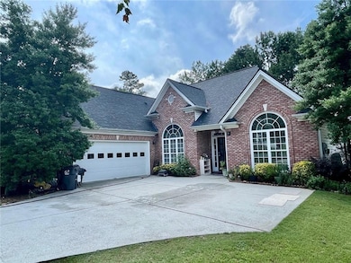 View of front of home featuring brick siding, an attached garage, driveway, and roof with shingles