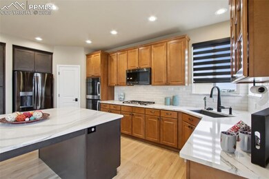Kitchen with stainless steel appliances, plenty of natural light, light wood finished floors, and brown cabinetry