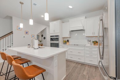 Kitchen with appliances with stainless steel finishes, light wood-type flooring, decorative backsplash, white cabinetry, and a kitchen breakfast bar