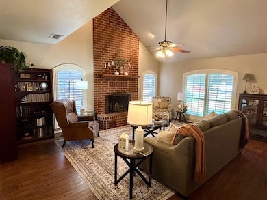 Living room with a fireplace, high vaulted ceiling, dark wood-type flooring, and a ceiling fan