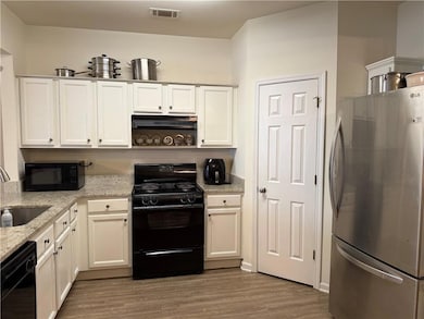 Kitchen featuring white cabinetry, black appliance