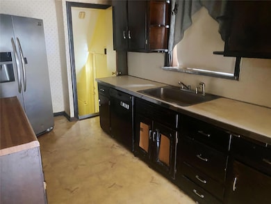 Kitchen featuring stainless steel fridge with ice dispenser, dishwasher, wallpapered walls, dark cabinets, and light flooring