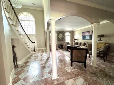 Entryway with arched walkways, decorative columns, stairs, ornamental molding, and baseboards