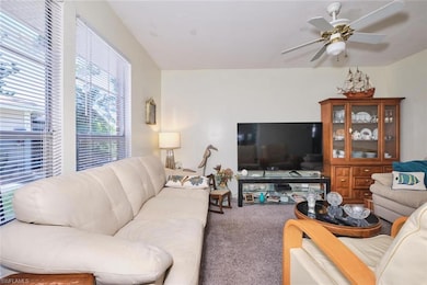 Living room featuring carpet and a ceiling fan