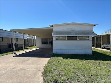 Manufactured / mobile home featuring an attached carport, concrete driveway, and a front yard