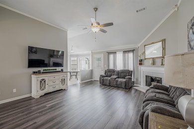 Living area featuring lofted ceiling, ceiling fan, a tile fireplace, baseboards, and ornamental molding