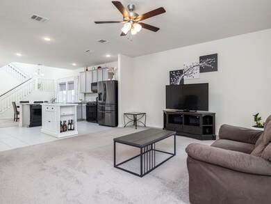 Living room with ceiling fan, stairs, a chandelie