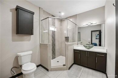 Full bathroom with a shower stall, toilet, vanity, baseboards, and tile patterned floors