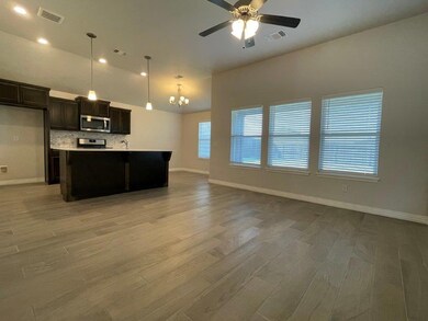 Kitchen featuring stainless steel microwave, light wood finished floors, open floor plan, a chandelier, and a ceiling fan