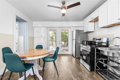 Kitchen featuring stainless steel appliances, french doors, wood finished floors, white cabinets, and ceiling fan