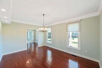 Unfurnished dining area with crown molding, dark wood-style flooring, a chandelier, and recessed lighting