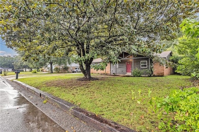 Obstructed view of property featuring a front yard, brick siding, and a shingled roof