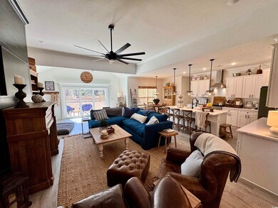 Living room featuring ceiling fan, light wood fini