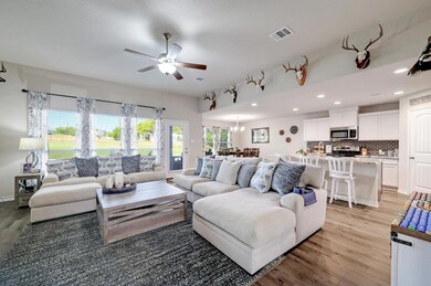 Living room featuring ceiling fan, light wood-sty
