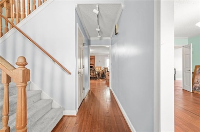 Corridor featuring a textured ceiling, crown molding, hardwood / wood-style flooring, and stairs