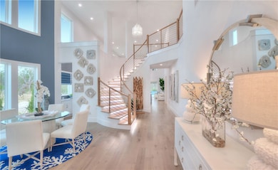 Foyer entrance featuring a high ceiling, light wood-style floors, stairs, and recessed lighting