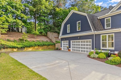 View of side of property with a gambrel roof, a garage, concrete driveway, fence, and a shingled roof