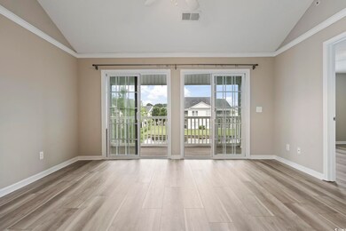 Spare room featuring lofted ceiling, healthy amount of natural light, wood finished floors, baseboards, and crown molding