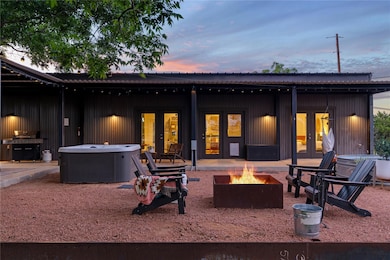 Back of house featuring a patio area, french doors, a hot tub, and a fire pit