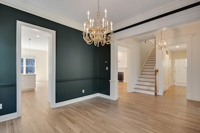 Unfurnished room featuring a chandelier, stairs, light wood finished floors, and crown molding