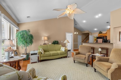 Living area with wood finished floors, a ceiling fan, high vaulted ceiling, and a chandelier