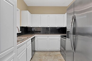 Kitchen with white cabinetry, appliances with stai
