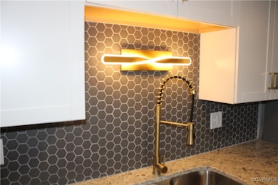 Kitchen view of white cabinets, backsplash, and li