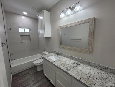 Bathroom featuring vanity, shower / bath combination, dark wood-type flooring, and recessed lighting