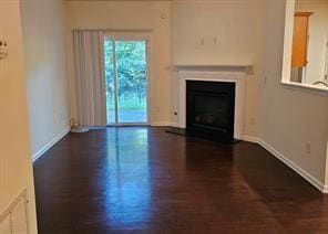 Unfurnished living room with a fireplace with flush hearth and dark wood-type flooring
