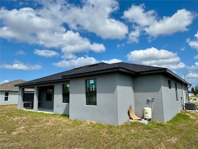 Rear view of property featuring a lawn, stucco siding, and a patio