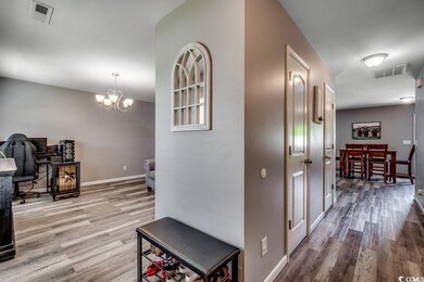 Hallway featuring wood finished floors, a chandelier, and a desk