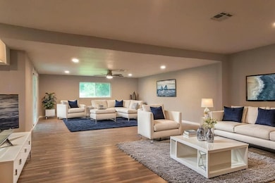 (Virtually Staged) Stylish room with white furniture, warm wood floors, and a cozy studio couch. Perfect for a modern living space, ideal for an upscale interior design.