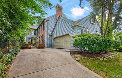 View of side of property featuring a chimney, driveway, an attached garage, and roof with shingles