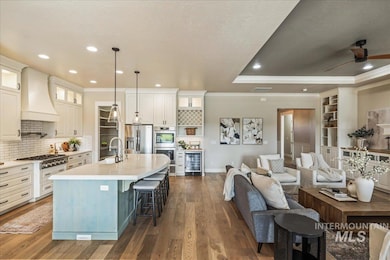 Kitchen with recessed lighting, a center island with sink, a breakfast bar, custom range hood, and pendant lighting