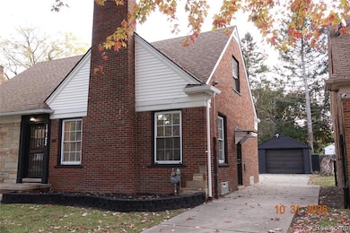 View of side of home featuring brick siding, a chimney, an outbuilding, concrete driveway, and a detached garage