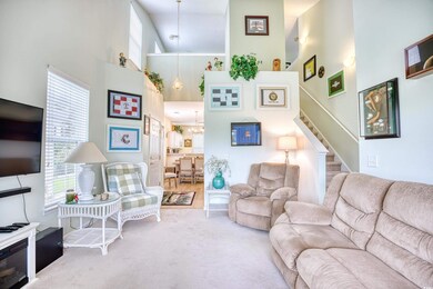 Living room featuring carpet, a towering ceiling, 