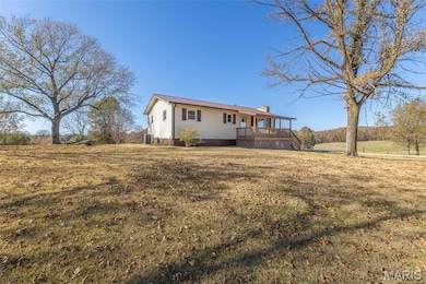 Rear view of house with a chimney, a lawn, and a porch