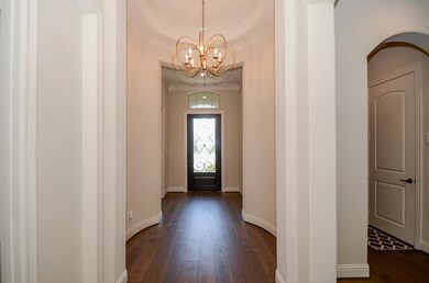 Your front entry from the inside is embraced by sophisticated, neutral wall colors and shining wood floors. Note the stunning architectual nuances, such as an oval, mini-tray ceiling in the foyer entrance and delicate, curved wall structures.