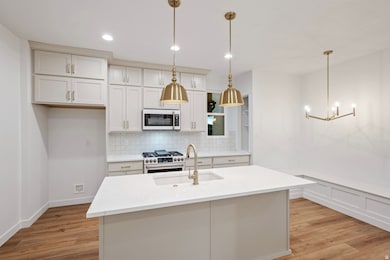 Kitchen featuring GE Cafe appliances tasteful backsplash, light wood finished floors, and decorative light fixtures