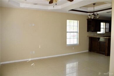 Kitchen with dark brown cabinets, a raised ceiling, light tile patterned floors, and a ceiling fan