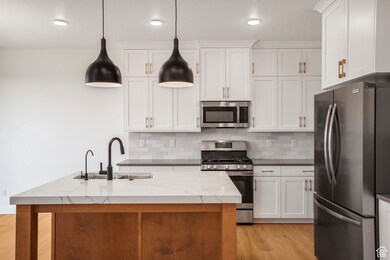 Kitchen with stainless steel appliances, hanging light fixtures, backsplash, dark stone counters, and recessed lighting