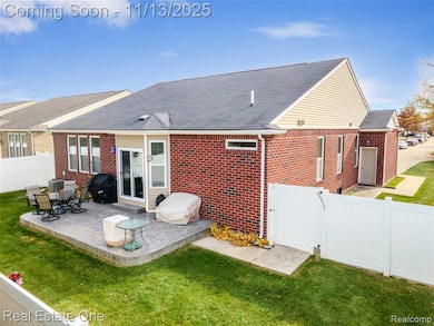 Rear view of house with a fenced backyard, roof with shingles, a gate, brick siding, and a patio area