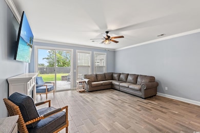 Living room featuring ornamental molding, ceiling fan, and wood finished floors